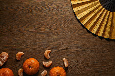 陆军象形摄影照片_在木制表面的新鲜成熟的橘子和金色的扇子与象形文字的顶部视图