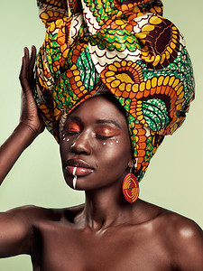 studio摄影照片_Do you know the history of the African head wrap. Studio shot of a beautiful young woman wearing a traditional African head wrap against a green background