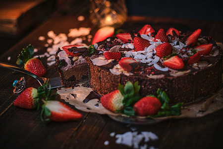 Vegan chocolate cake with strawberries, cocnut shovel and raspberry seeds, served on a paper serviette