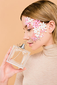 有吸引力的花在脸上闻到的香水隔离在米色