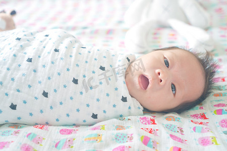 可爱可爱的婴儿男孩裹在毯子或襁褓, 睡觉, 有时两只眼睛打开在儿童床上