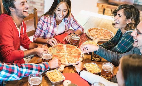 家人团聚时在家里吃披萨时，年轻的朋友们笑得正正正正经经。与快乐的人在比萨饼店一起享受欢乐时光的友谊概念。温情生动的过滤