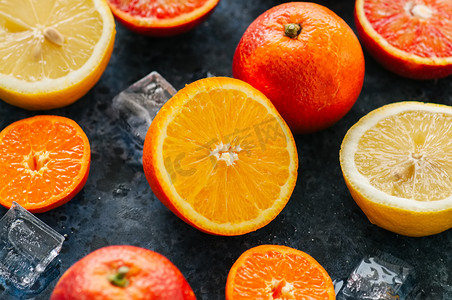混合新鲜成熟的柑橘类水果为血橙, mandarines, 柠檬与冰块在蓝色的石头背景。顶部视图.