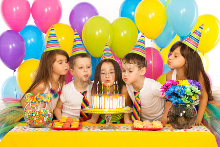 吹摄影照片_孩子们庆祝生日聚会和吹蛋糕上的蜡烛