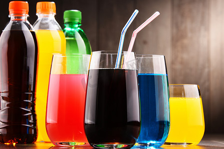碳酸摄影照片_各种颜色的各式碳酸软饮料的玻璃和瓶子