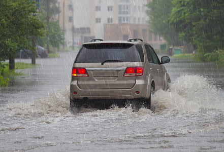 洪水泛滥摄影照片_在洪水泛滥的道路上，汽车在大雨中行驶