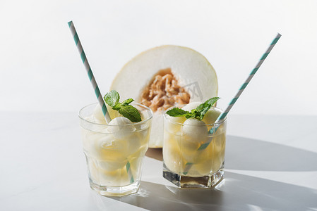 夏季饮料的特写视图与瓜和薄荷在玻璃和半成熟的哈密瓜白色 
