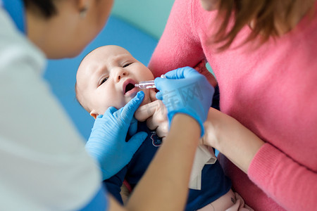 婴儿在母亲的手在医院。护士对婴幼儿轮状病毒感染进行口服疫苗接种。儿童保健与疾病预防