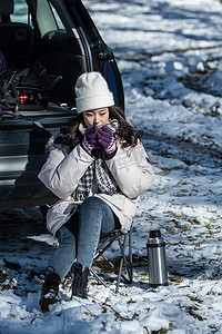 烧水壶水垢摄影照片_坐在汽车旁喝热水的青年女人