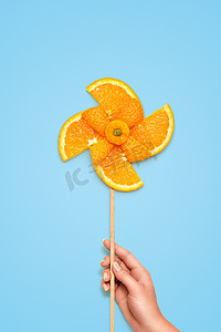 果味风车。黄色玩具风车的创意静生活，由蓝色背景上的新鲜橙色切片制成.
