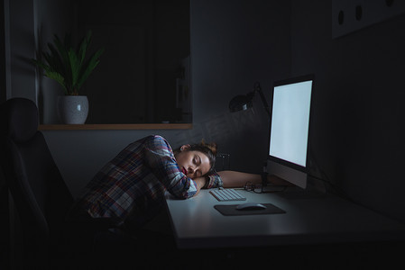 电脑前摄影照片_年轻的女商人在深夜工作在电脑前的桌子上睡着.