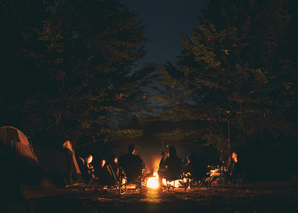 篝火摄影照片_这群年轻人围坐在篝火边，一边聊天一边唱歌