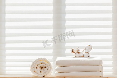 白色的亚麻布床单，有一个棉枝和一条毛巾布靠窗的背景。自然组成.