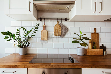 厨房黄铜器皿，厨师配件。用白色瓷砖墙和木制桌布挂厨房。厨房背景图上的绿色植物