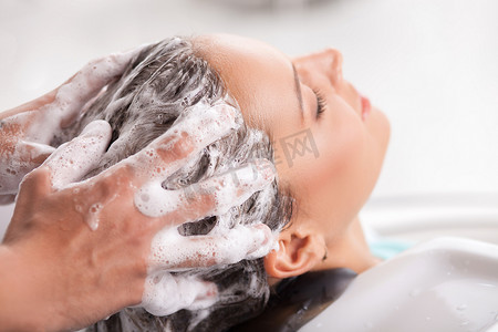 Cheerful young woman has her hair washed in beauty shop