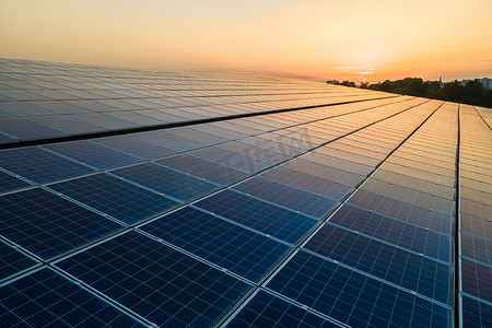 光电logo摄影照片_蓝色光电太阳能电池板安装在建筑物的屋顶上，以便在日落时产生清洁的生态电力。可再生能源概念的生产