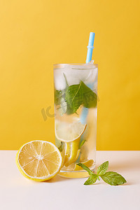 柠檬水加柠檬、薄荷糖和冰块，多汁的杯子加稻草，新鲜的夏季饮料加柠檬片放在桌上.