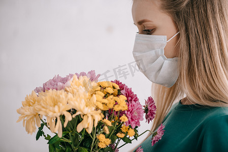 金发碧眼的妇女与花粉过敏戴着医疗面具, 看着花束的花束 
