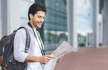机场地图摄影照片_快乐的千禧一代男子计划他的度假路线与纸质地图