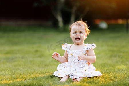 crying baby toddler girl on grass outdoors. Child feelings and emotions concept. Sad expression. Childhood. copy space