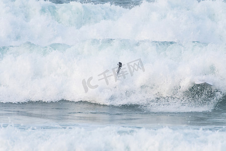 在西班牙北部海岸的海滩上，冲浪手被巨浪吞没了