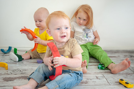 三个孩子拿着玩具坐在儿童房里