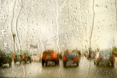 focusing摄影照片_Street in the rain through the window of the car, on a cold, wet day, shot through a windscreen, focusing on the rain droplets. with copy space for your text on the sky.