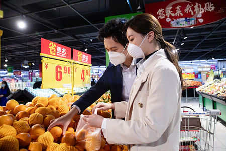 水果摄影照片_青年夫妇戴口罩在超市挑选水果