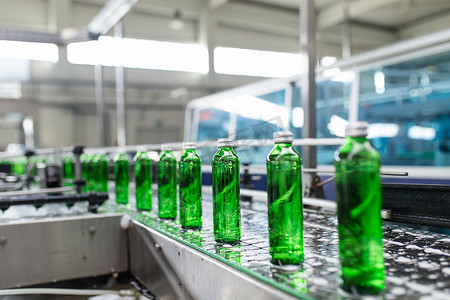 装瓶摄影照片_装瓶厂 - 水装瓶生产线，用于加工纯泉水并将其装瓶成绿色玻璃瓶。选择性聚焦. 