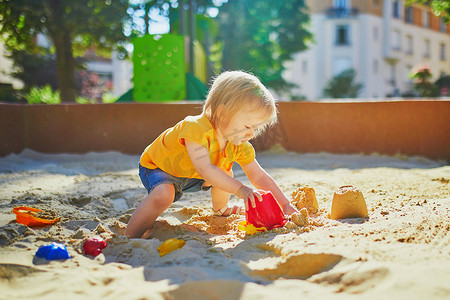 沙坑摄影照片_小女孩在沙坑的操场上玩得很开心