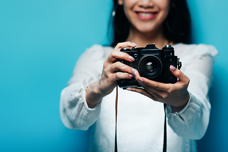 数码相机白摄影照片_身着白衬衫、头戴蓝色背景数码相机、面带微笑的亚洲女人的剪影