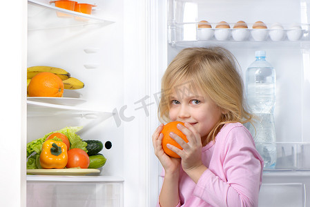 小女孩抱着橙色附近打开冰箱