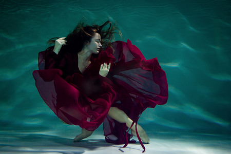 跳舞的妇女在水下在水池在红色礼服.