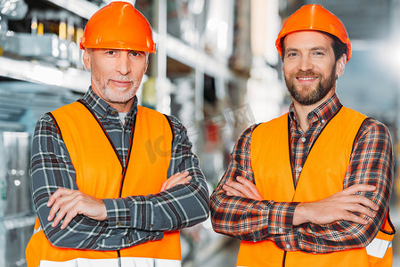 两名男性工人穿着安全背心和带交叉臂的头盔