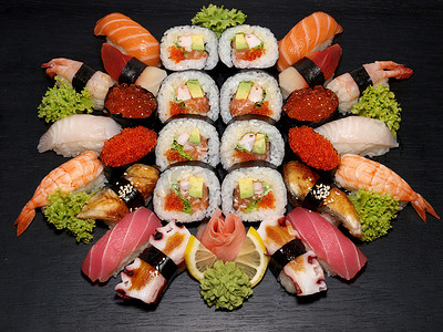 Sushi and roll set on a black wooden background.