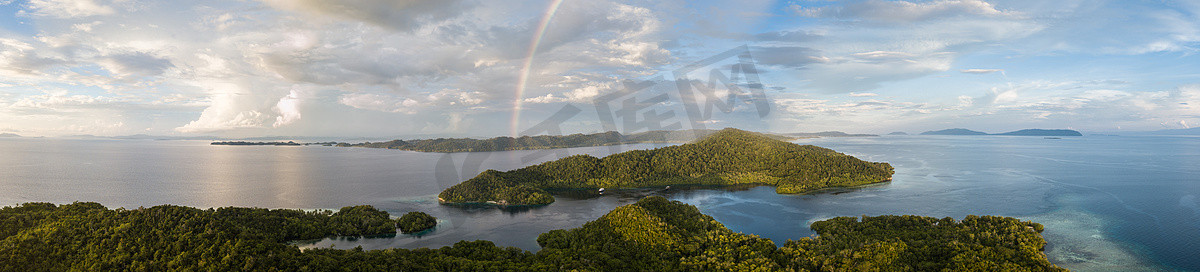 热带地区摄影照片_一条彩虹出现在印尼 Ampat 的一座美丽的岛屿上。这个热带地区被称为 