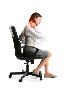 neck摄影照片_Young businesswoman in back brace suffering from pain in neck while sitting on chair against white background