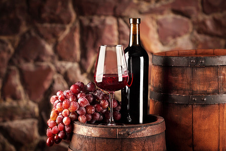 红酒。静物与玻璃和瓶红酒、 葡萄和桶。选择性的焦点。酒窖的气氛。复制空间
