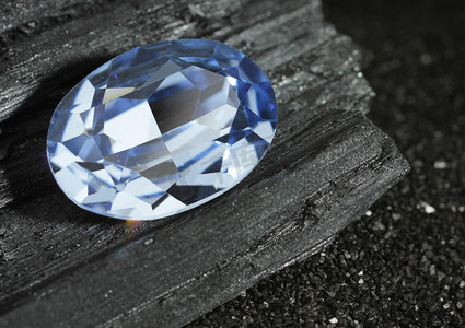 蓝宝石表镜摄影照片_黑煤背景上分面的蓝色珠宝宝石蓝宝石