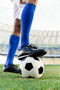 足球场上穿着蓝色袜子和足球鞋的职业足球运动员的腿