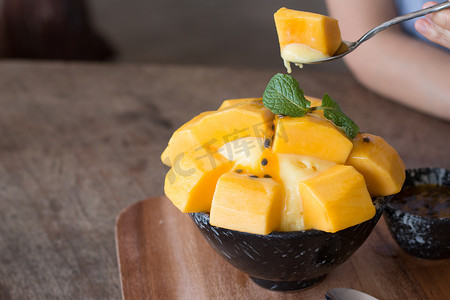 在木制桌子上的陶瓷碗里重新装饰芒果冰激凌和西番莲水果，作为夏天最受欢迎的甜点.