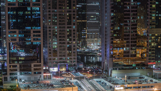 与照明摩天大楼夜间 timelapse 与汽车停放和交通在酋长扎耶德路和地铁线的朱美拉湖塔鸟瞰。从迪拜码头的屋顶景观