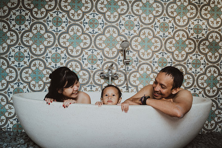 happy family with little daughter in bathtub