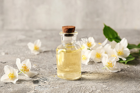 Bottle of essential oil and jasmine flowers on grunge background