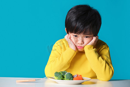 健康休闲食品摄影照片_盯着蔬菜发愁的小男孩