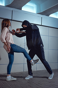 妇女保护自己免受攻击小偷在地下通道的黑色连帽衫