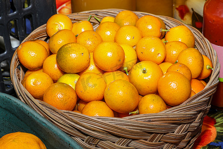 orange摄影照片_Basket with several organic kumquat tangerines, a berry that looks like a miniature oval orange and has a bitter citrus taste