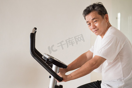 高级老人骑自行车，锻炼身体，工作在健身房与模式