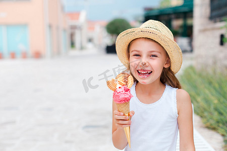 有趣的孩子在吃冰淇淋。孩子们正享受着融化的意大利明胶.戴着草帽的快乐可爱的女孩在笑