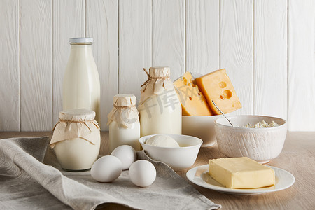 鲜美口感的鹅肝摄影照片_白色木制背景的鲜美鲜奶产品和蛋类